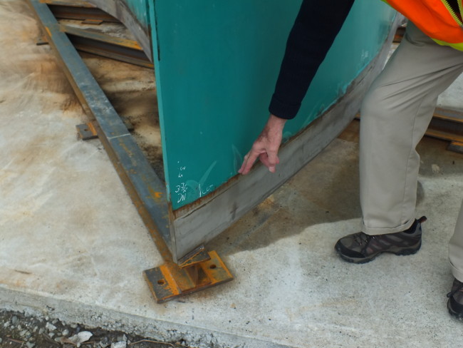 Robert Murray shows where the sculpture was cut away from its bottom at the Dimond Court Plaza in 1984 and then restored with new steel this winter. Also visible is the new steel framework constructed for the bottom. (Photo by Matt Miller/KTOO)